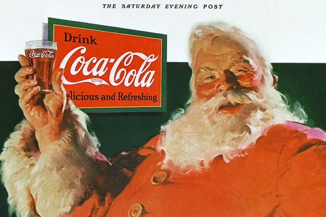 Santa Claus holding a glass of Coca-Cola with a Drink Coca-Cola sign in the background.