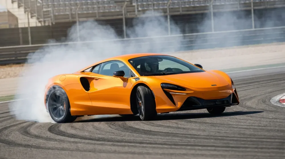 Orange McLaren Artura supercar drifting on a race track